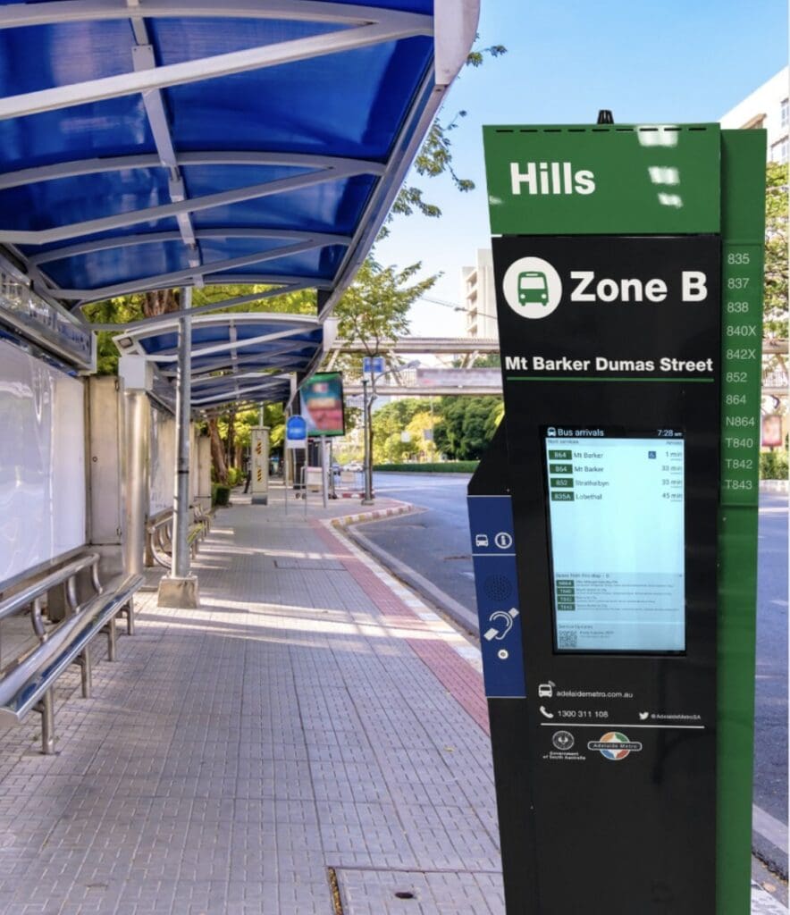 This is an image of a digital Bust stop totem with built in voice annunciator and hearing loop by metrospec installed at a bus stop.