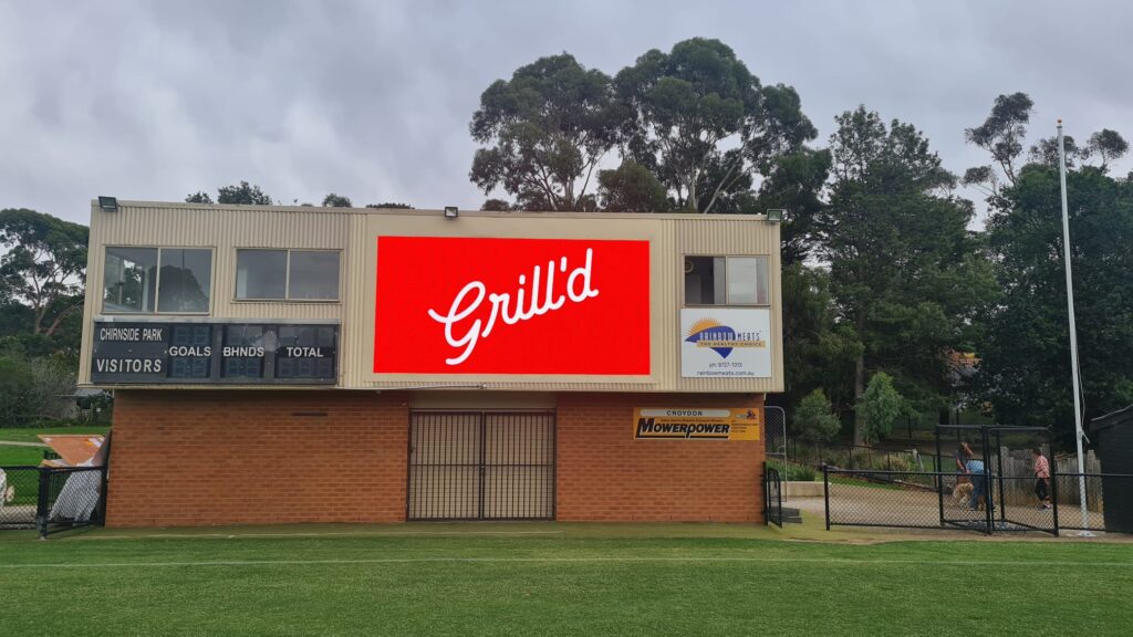 LED scoreboard showing AFL match scores and sponsor advertisements